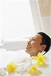 Woman in bathtub, smiling, looking away