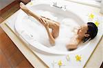 Woman in bath tub washing leg, high angle view