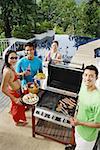 Couples having a barbeque, looking at camera