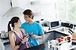 Couple standing in kitchen, holding wine glasses
