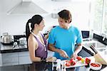 Couple standing in kitchen, man chopping vegetables