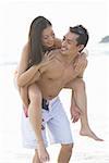 Couple on beach, woman riding piggyback on man