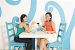 Young women in cafe, toasting with wine glasses, smiling at camera