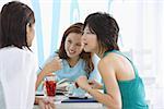 Three young women sitting in cafe talking