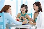 Three young women sitting in cafe laughing