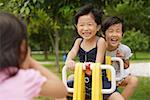 Young girls in playground, playing on seesaw