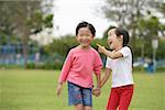 Young girls holding hands in park laughing