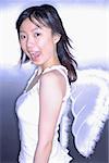 Young woman wearing angel wings, looking at camera, mouth open