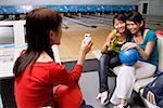 Women in bowling alley, posing for friends phone camera