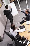 Group having a business meeting, man writing on flipchart