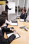 Business people in meeting, woman writing on flipchart