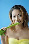 Woman looking at camera, eating celery