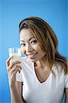 Woman holding a glass of milk, smiling at camera
