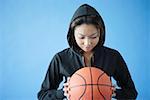 Woman wearing hooded shirt, holding basketball