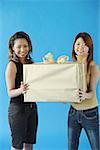 Two woman carrying big gift box, smiling