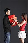 Young man holding gift, facing young woman