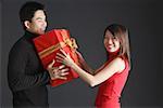 Young man giving gift to woman, woman turning to smile at camera