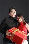 Couple holding gift, looking at camera