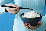 Woman holding bowl of rice and chopstick