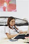 Girl sitting on bed, using laptop