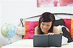 Girl lying on bed, writing in diary