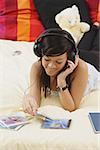 Girl lying on bed, listening to headphones