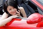 Woman sitting in convertible, looking at herself in side view mirror