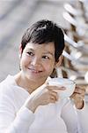 Mature woman holding coffee cup, looking away, smiling