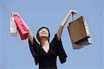 Woman arms outstretched, carrying shopping bags