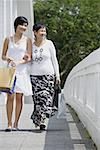 Women walking arm in arm, along bridge