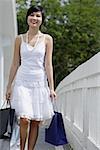 Woman carrying shopping bags, walking along bridge