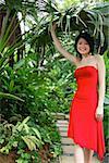 Femme vêtue d'une robe rouge, debout dans le jardin