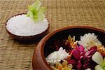 Still life of flowers in bowl and a single flower head on bowl of rice