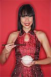 Woman against red background, dressed in cheongsam, holding bowl of rice