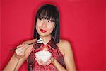 Woman against red background, holding bowl of rice