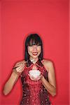 Woman dressed in red cheongsam, eating bowl of rice