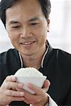 Man looking at bowl of rice in his hands