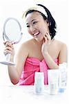 Young woman sitting at dressing table, looking in mirror, hand on chin