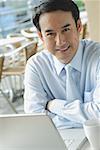 Businessman in cafe with laptop, smiling at camera