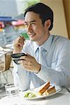 Businessman in cafe, using PDA, smiling