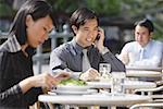 Business people at outdoor café, focus on man using mobile phone