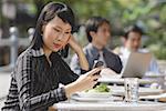 Businesswoman using mobile phone at outdoor cafe, text messaging