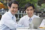 Businessmen at outdoor cafe, smiling at camera