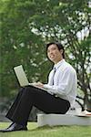 Businessman sitting in park with laptop