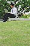 Businessman sitting in park using laptop