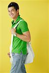 Man in green polo shirt, standing against yellow background, sunglasses on