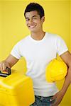 Man carrying construction hat and toolbox, smiling at camera