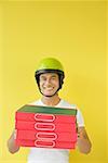 Pizza delivery person carrying a stack of pizza boxes