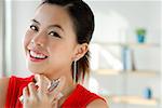 Young woman spraying perfume, smiling at camera