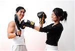 Young woman with boxing gloves, practicing with trainer